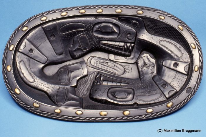 Haida Argilite platter made in the 1880s, showing two killer wales. The rim is inlaid with opercula, sea snail "plugs". (42ch, MOA)