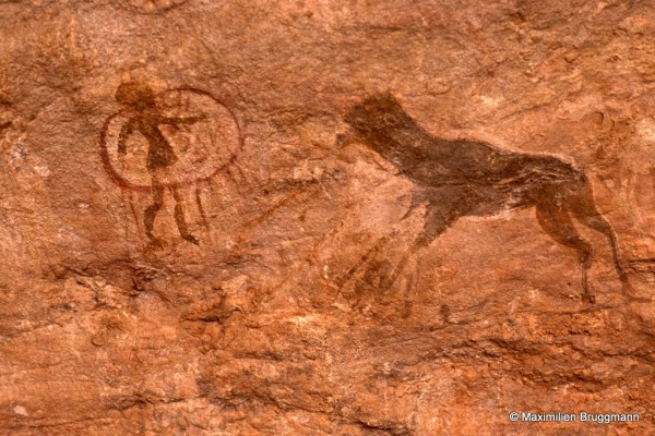 539 Tan-Zoumaïtak (Tassili-n'Ajjer). — Cette peinture à l'ocre rouge nous présente, à gauche, un petit personnage à ample chevelure en partie inséré dans un cercle d'où pendent des lanières. L'animal de droite est peut-être un mouton brun foncé. Le cercle mesure 0,20 m de diamètre.